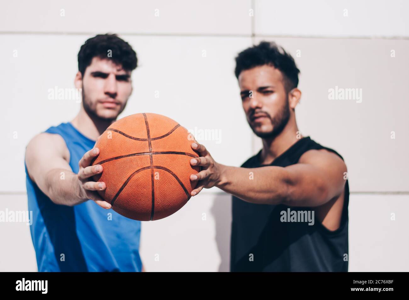 due giocatori di basket di diverse razze tengono insieme una palla Foto Stock