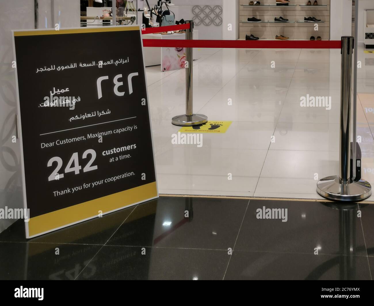 Un cartello di fronte a un negozio nel centro commerciale Qatar che indica il limite del numero di clienti ammessi all'interno durante la pandemia di virus corona. Nuovo normale Foto Stock