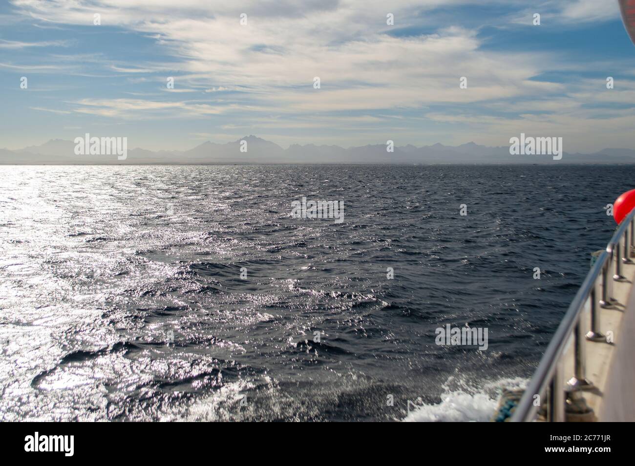 Vista da yacht a orizzonte mare. Le onde blu del Mar Rosso, le onde del mare riflettono la luce del sole, la vista a bordo dello yacht turistico e le nuvole sopra l'orizzonte. Foto Stock