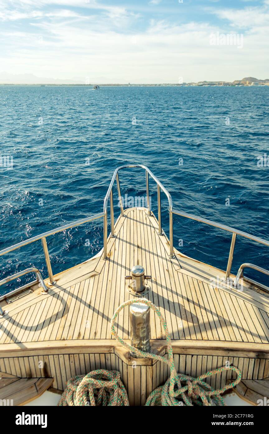 Vista da prua di yacht turistico a onde marine, l'isola mal, orizzonte. Onde Ultamarine del Mar Rosso. Vista dell'arco dello yacht alle onde del mare e dell'isola all'orizzonte Foto Stock