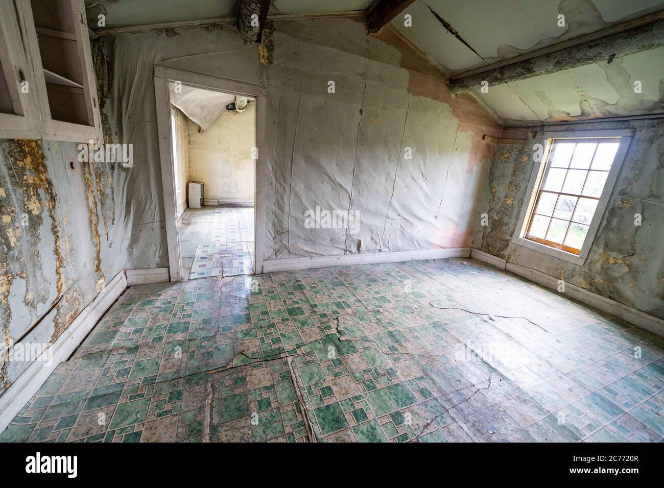 All'interno di un edificio abbandonato e decadente nella città fantasma di Bannack, nel Montana. Le pareti in marciume e il pavimento in linoleum sono incrinati Foto Stock