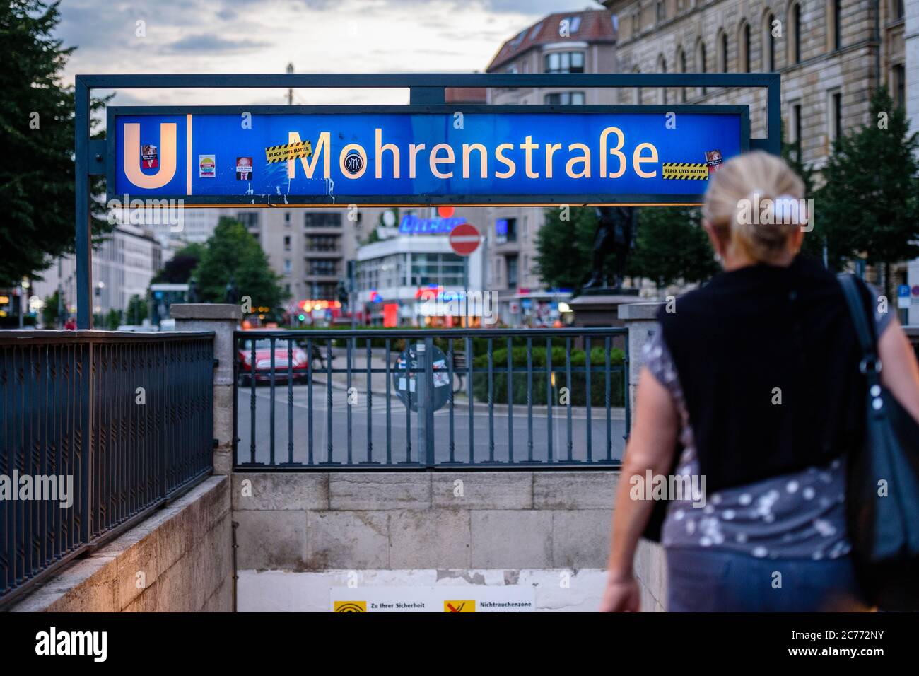 14 luglio 2020, Berlino, Berlino, Germania: Una donna si vede di fronte all'ingresso della stazione della metropolitana 'Mohrenstrasse'. Dagli anni '90 a Berlino si discute di una nuova denominazione della 'Mohrenstrasse' e della stazione della metropolitana omonima, nel contesto di un dibattito più ampio sui nomi delle strade che possono essere storicamente accusati. 'mohr' è un termine di discriminazione di lingua tedesca obsoleta per le persone di colore. Nel luglio 2020, la compagnia di trasporti pubblici di Berlino BVG ha deciso di rinominare la stazione della metropolitana "ohrenstraÃŸe". Anche il nuovo nome originale ''GlinkastraÃŸe'' è stato eliminato Foto Stock