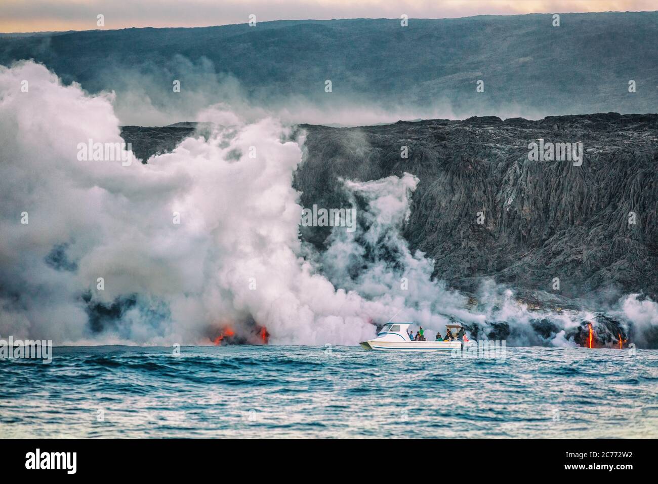 Tour in barca con eruzione del vulcano delle Hawaii. I turisti in crociera sull'oceano viaggiano attività guardando la lava che raggiunge l'acqua con fumi tossici. Escursione pericolosa Foto Stock