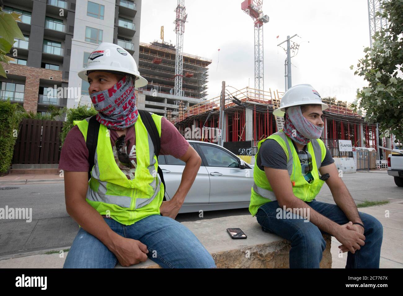 Austin, Texas USA 14 luglio 2020: I lavoratori del settore edile ascoltano le informazioni sulla sicurezza mentre si preparano per un turno di otto ore nel calore a 105 gradi del Texas. Gli equipaggi sono al secondo piano di un edificio a 53 piani, mentre prendono precauzioni contro la pandemia del coronavirus. Foto Stock