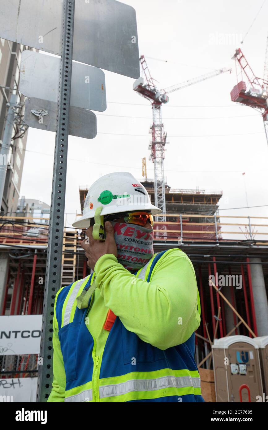 Austin, Texas USA 14 luglio 2020: I lavoratori del settore edile ascoltano le informazioni sulla sicurezza mentre si preparano per un turno di otto ore nel calore a 105 gradi del Texas. Gli equipaggi sono al secondo piano di un edificio a 53 piani, mentre prendono precauzioni contro la pandemia del coronavirus. Foto Stock