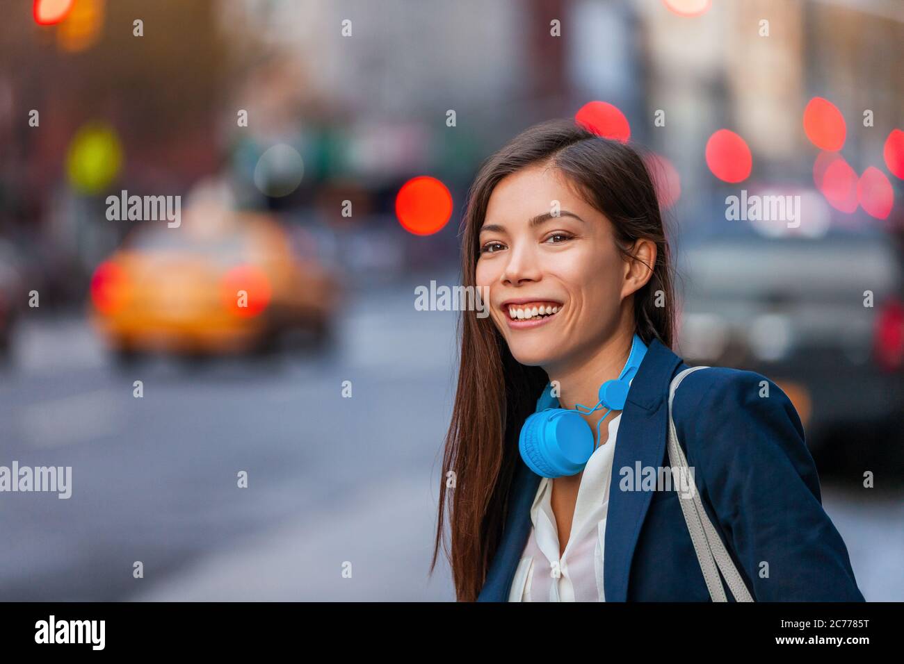 Giovane donna asiatica professionista hip con dispositivi tecnologici cuffie camminare su NYC New York City Street pendendo dopo il lavoro di notte. Felice sorridente Foto Stock