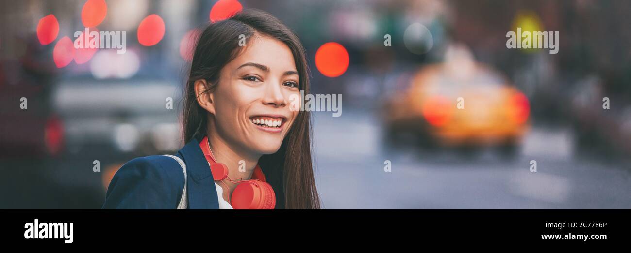 Gente città stile di vita giovane donna asiatica felice che cammina in New York City strada sfondo urbano con le cuffie rosse. Intestazione banner panoramica Foto Stock
