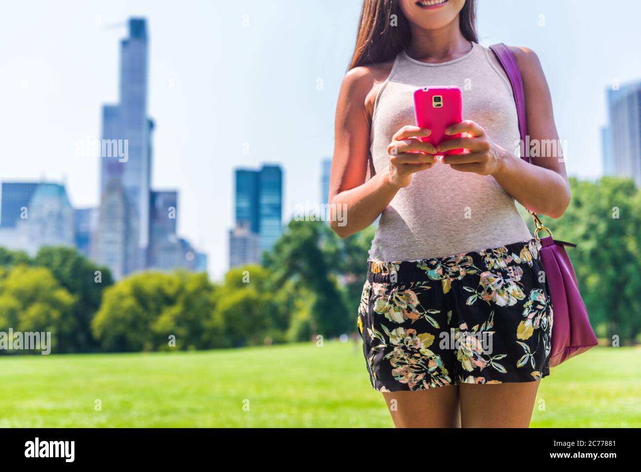 Urban Modern New York City lifestyle smartphone donna. Persona che invia SMS sul cellulare nel Central Park Meadow, New York. Vacanze estive Foto Stock