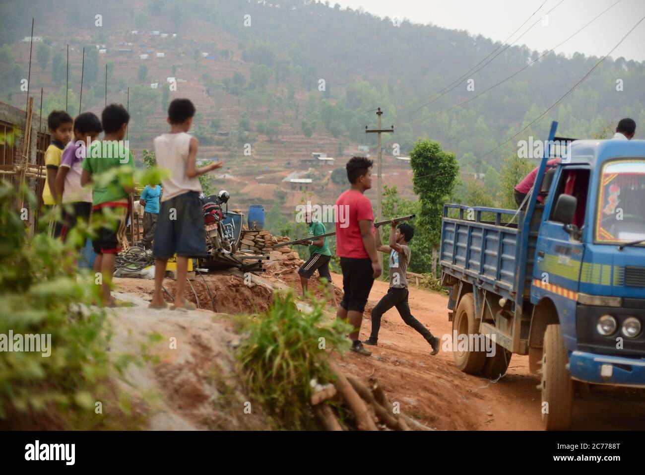 Uomini che scaricano materiali da costruzione da un camion in una zona rurale del distretto di Kavrepalanchok, provincia di Bagmati Pradesh, Nepal. Foto Stock