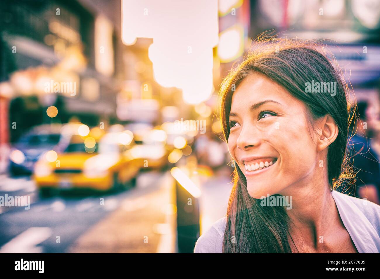 Happy People New York City lifestyle giovane donna asiatica sorridente al tramonto a piedi in strada con taxi traffico sole splendere in centro Foto Stock