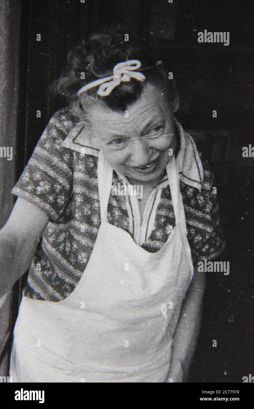 Fine anni 70 vintage nero e bianco stile di vita fotografia di una nonna  anziana nel suo grembiule di cottura prendendo una pausa dalla cucina e  andando fuori Foto stock - Alamy