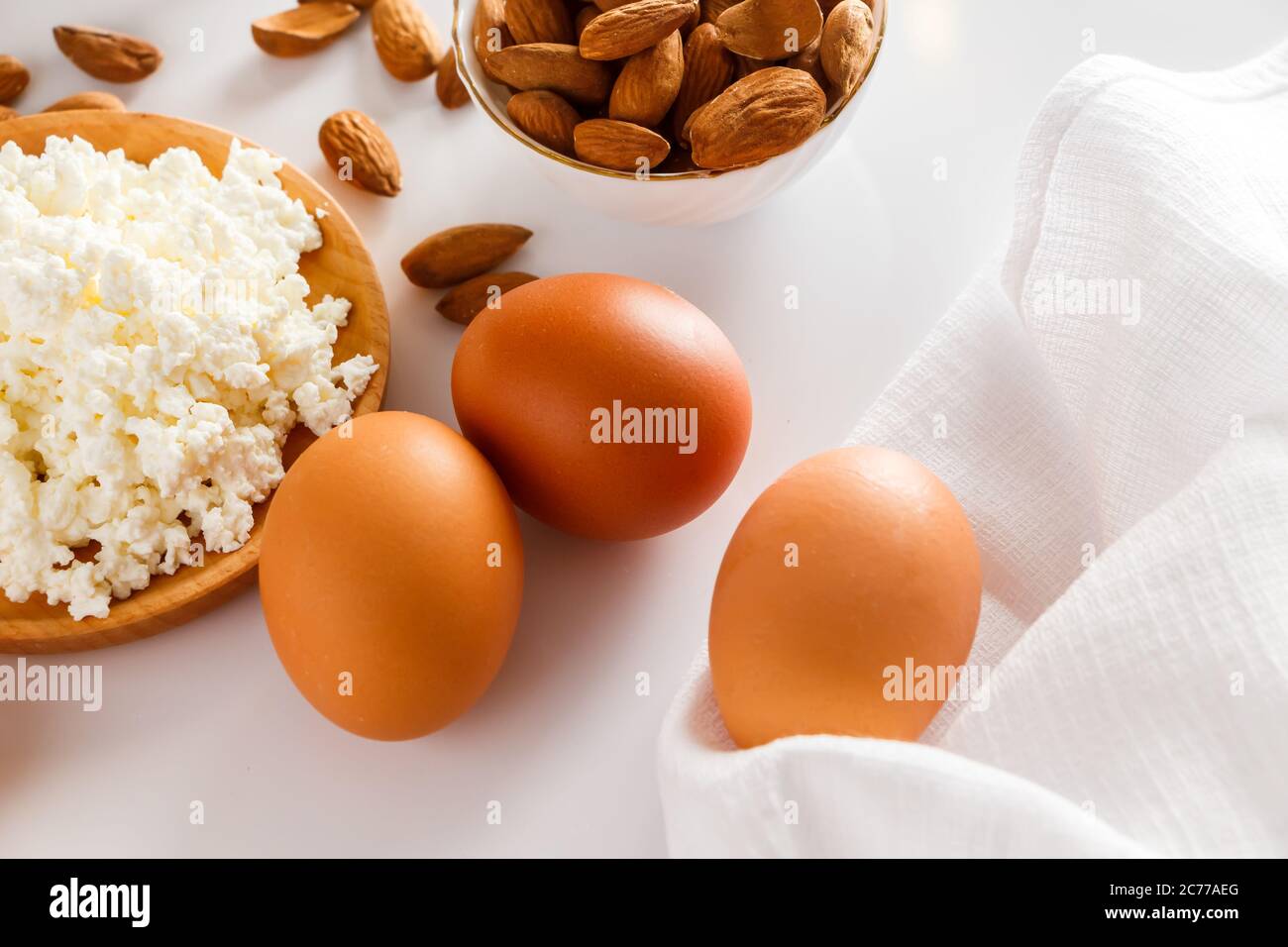 Un insieme di alimenti proteici sani per una dieta equilibrata. Ricotta formaggio, uova e noci su sfondo bianco. Foto Stock Un insieme di alimenti proteici sani per una dieta equilibrata. Ricotta formaggio, uova e noci su sfondo bianco. Foto Stock