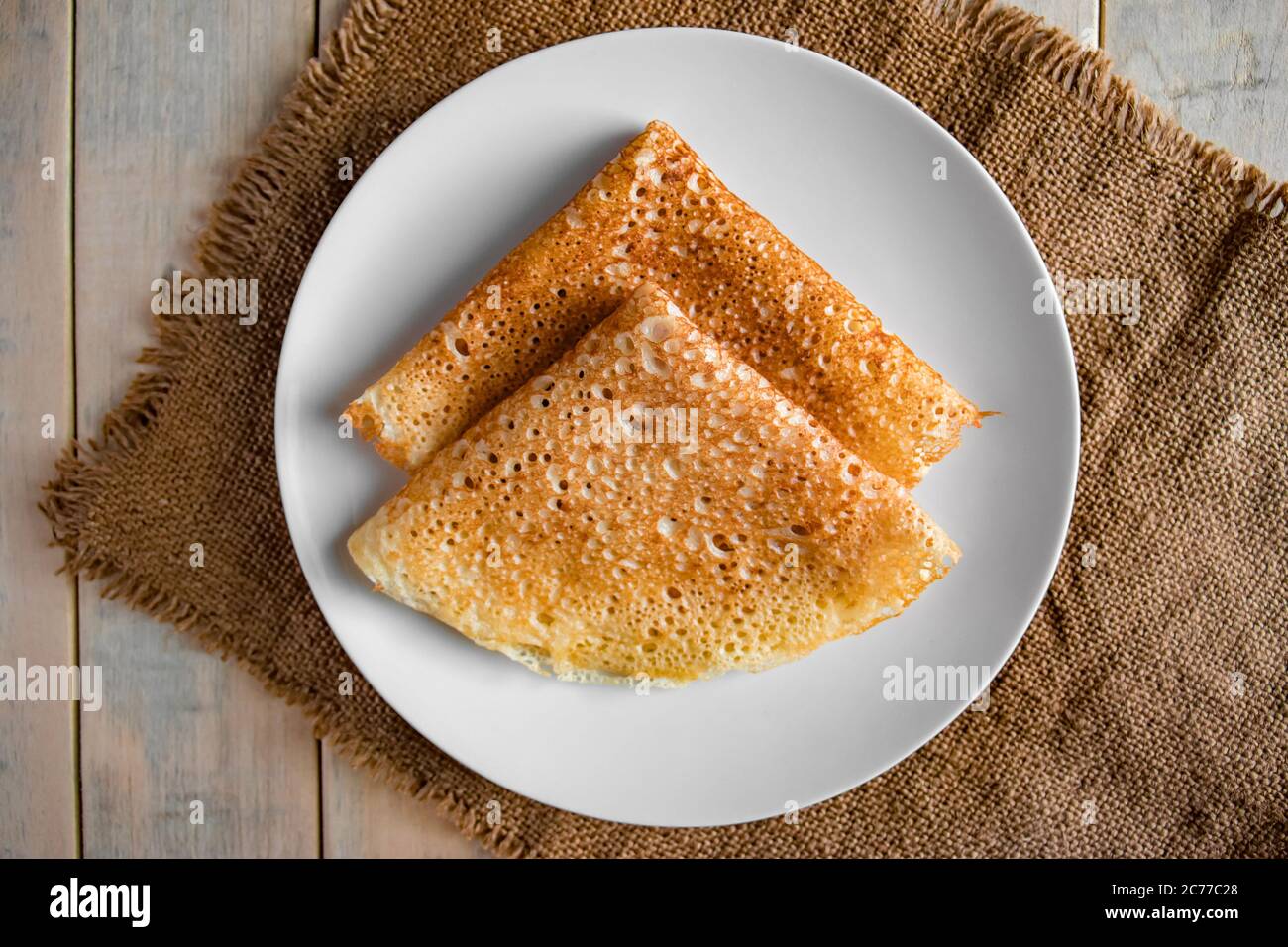 Pancake su un piatto bianco su uno sfondo di lino. Crepes di cibo tradizionale russo per la vacanza Maslenitsa. Disposizione piatta Foto Stock