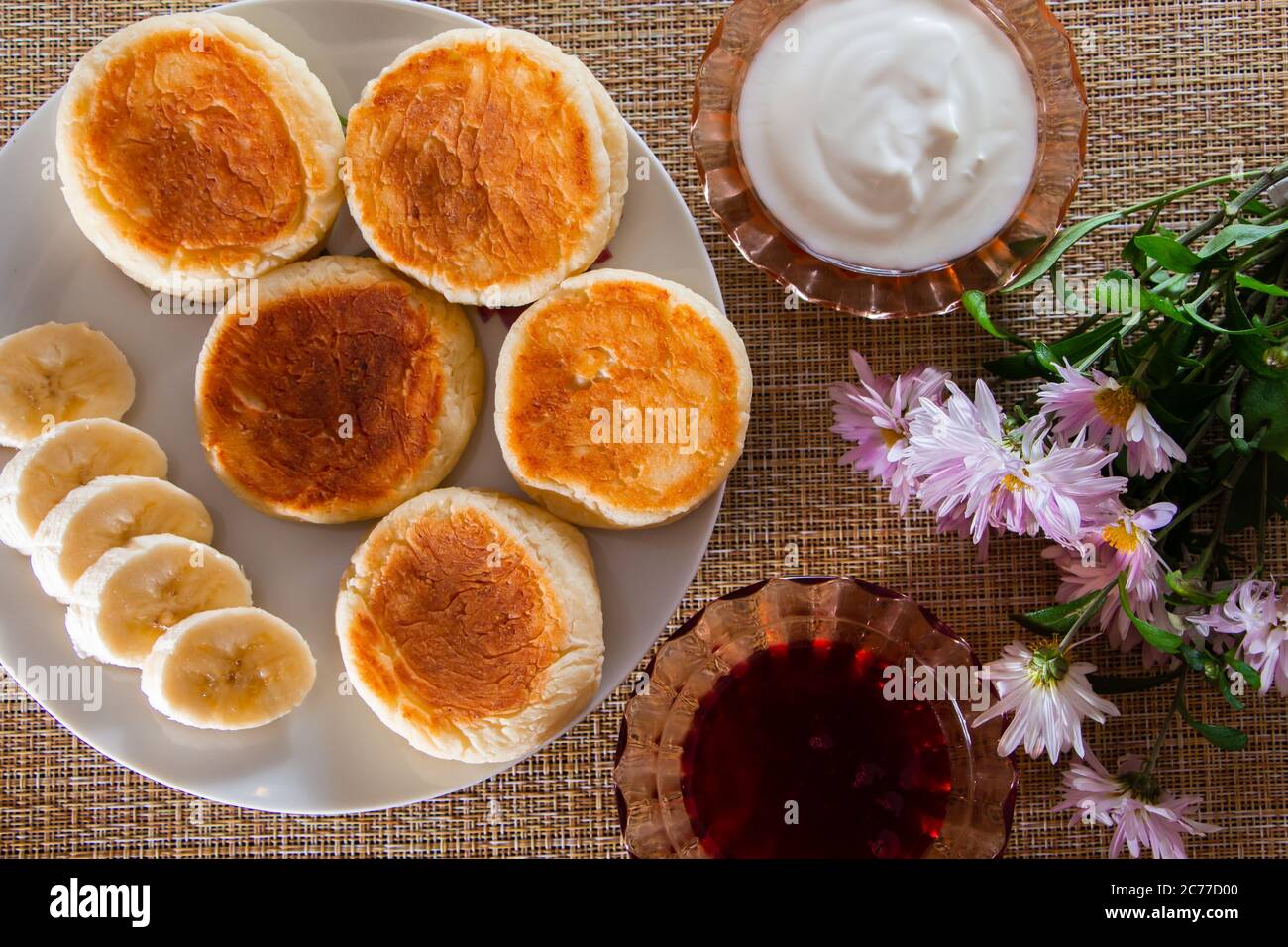 Colazione fatta in casa - deliziosi frittelle di formaggio cottage su un piatto con marmellata e panna acida. Foto Stock