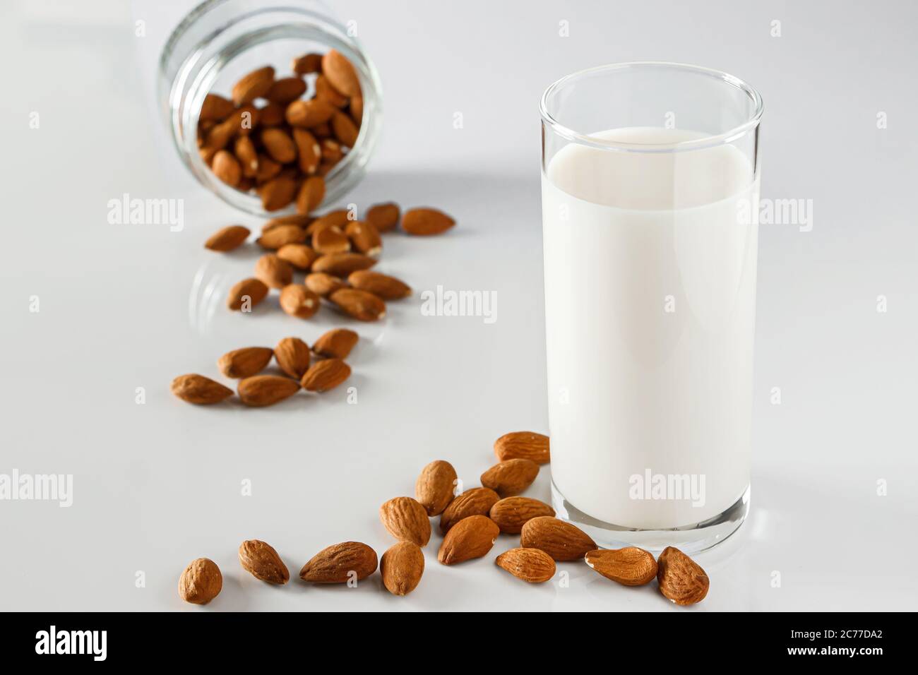 Un bicchiere di latte di mandorle su fondo bianco. Latte alimentare vegetale senza lattosio. Bevanda senza glutine di mandorle su sfondo blu. Super Food - UN bicchiere di Foto Stock Un bicchiere di latte di mandorle su fondo bianco. Latte alimentare vegetale senza lattosio. Bevanda senza glutine di mandorle su sfondo blu. Super Food - UN bicchiere di Foto Stock
