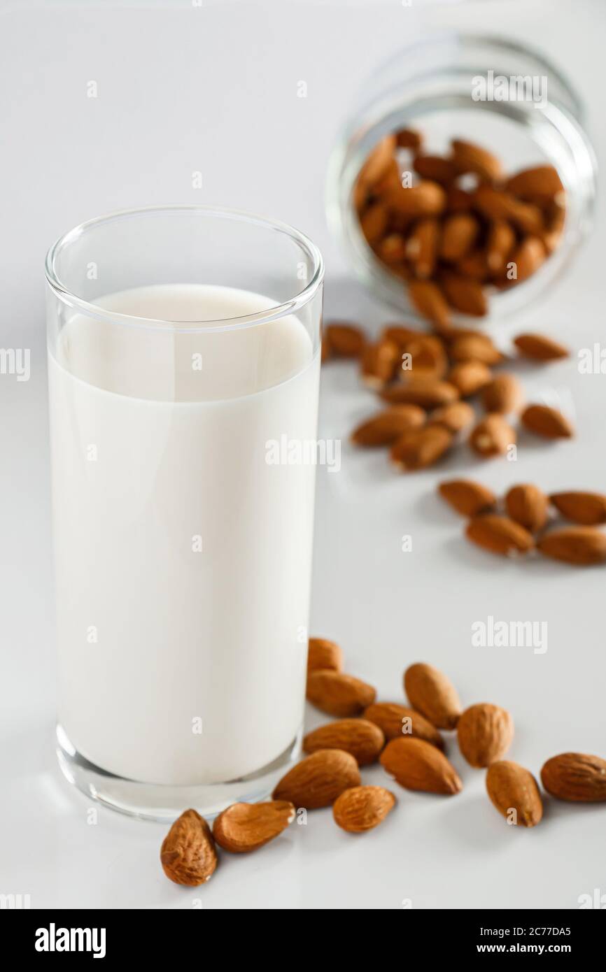 Un bicchiere di latte di mandorle su fondo bianco. Latte alimentare vegetale senza lattosio. Bevanda senza glutine di mandorle su sfondo blu. Super Food - UN bicchiere di Foto Stock