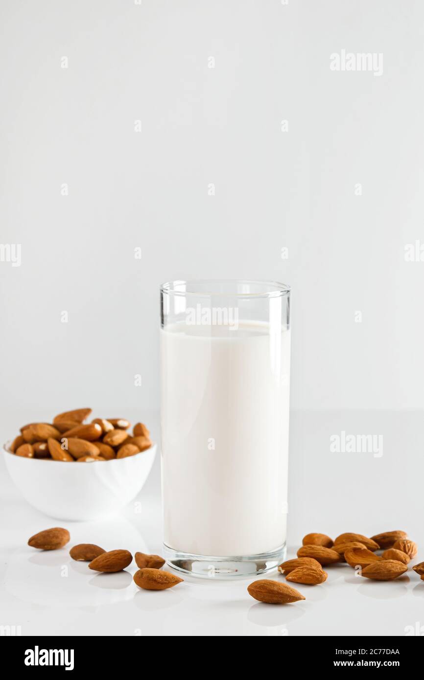 Un bicchiere di latte di mandorle su fondo bianco. Latte alimentare vegetale senza lattosio. Bevanda senza glutine di mandorle su sfondo blu. Super Food - UN bicchiere di Foto Stock