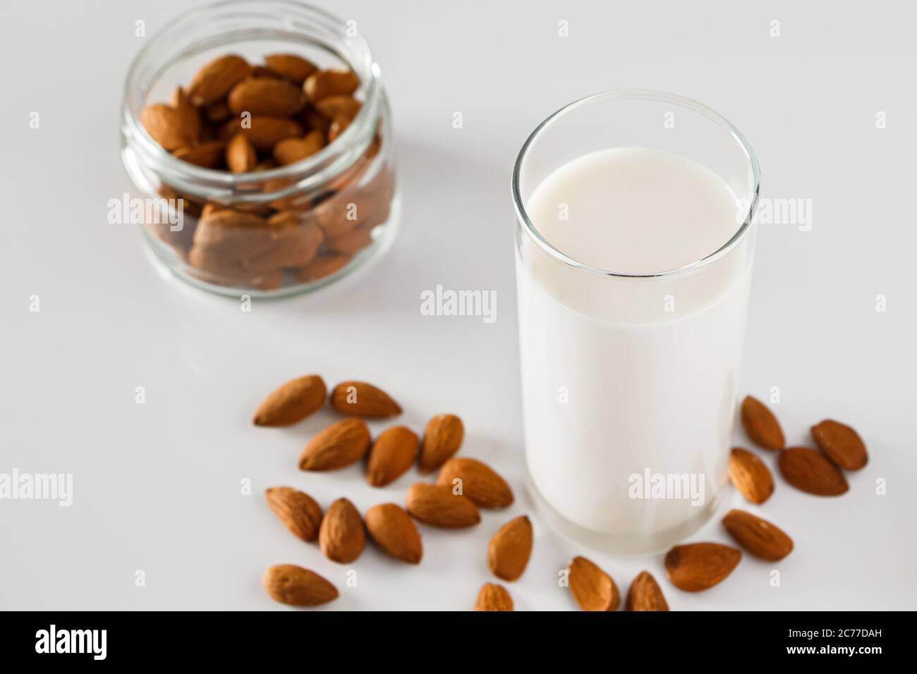 Un bicchiere di latte di mandorle su fondo bianco. Latte alimentare vegetale senza lattosio. Bevanda senza glutine di mandorle su sfondo blu. Super Food - UN bicchiere di Foto Stock