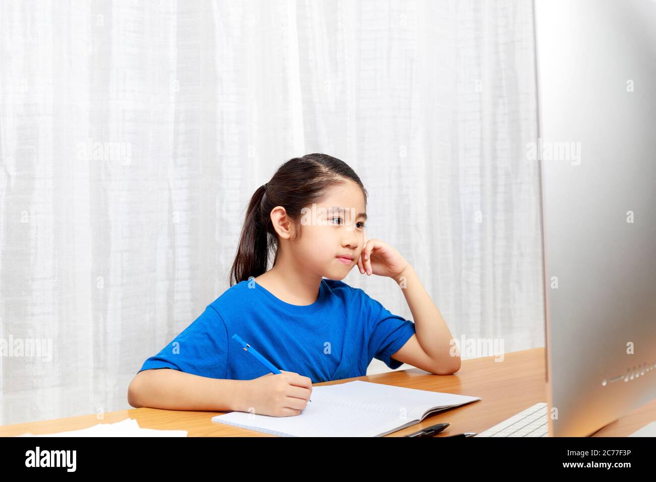 La bambina asiatica sta studiando in linea via il Internet che siede e scrive nel soggiorno a casa. Asia bambini scrivere con matita su notebook. Onl Foto Stock