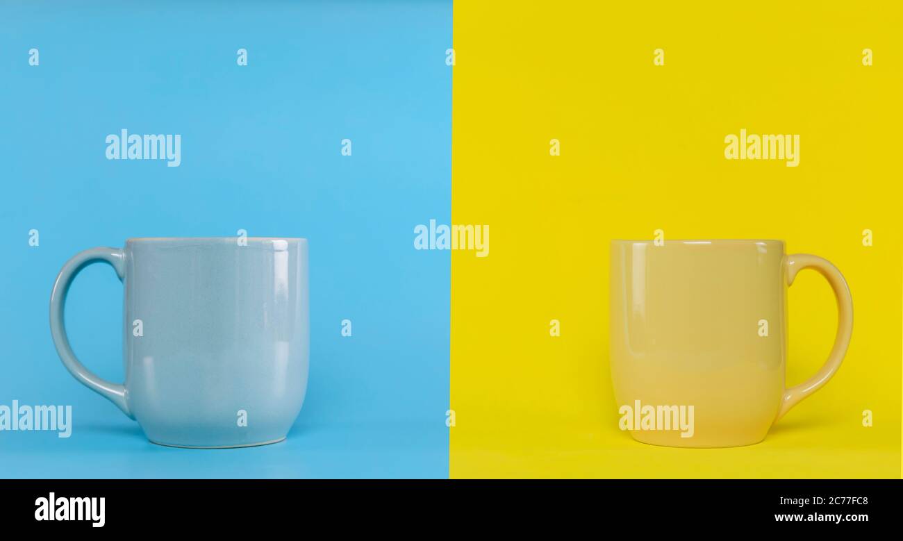 Coppa blu su sfondo blu e tazza gialla su sfondo giallo con spazio per la copia. Tazza blu con manico e gialla con manico. Foto Stock