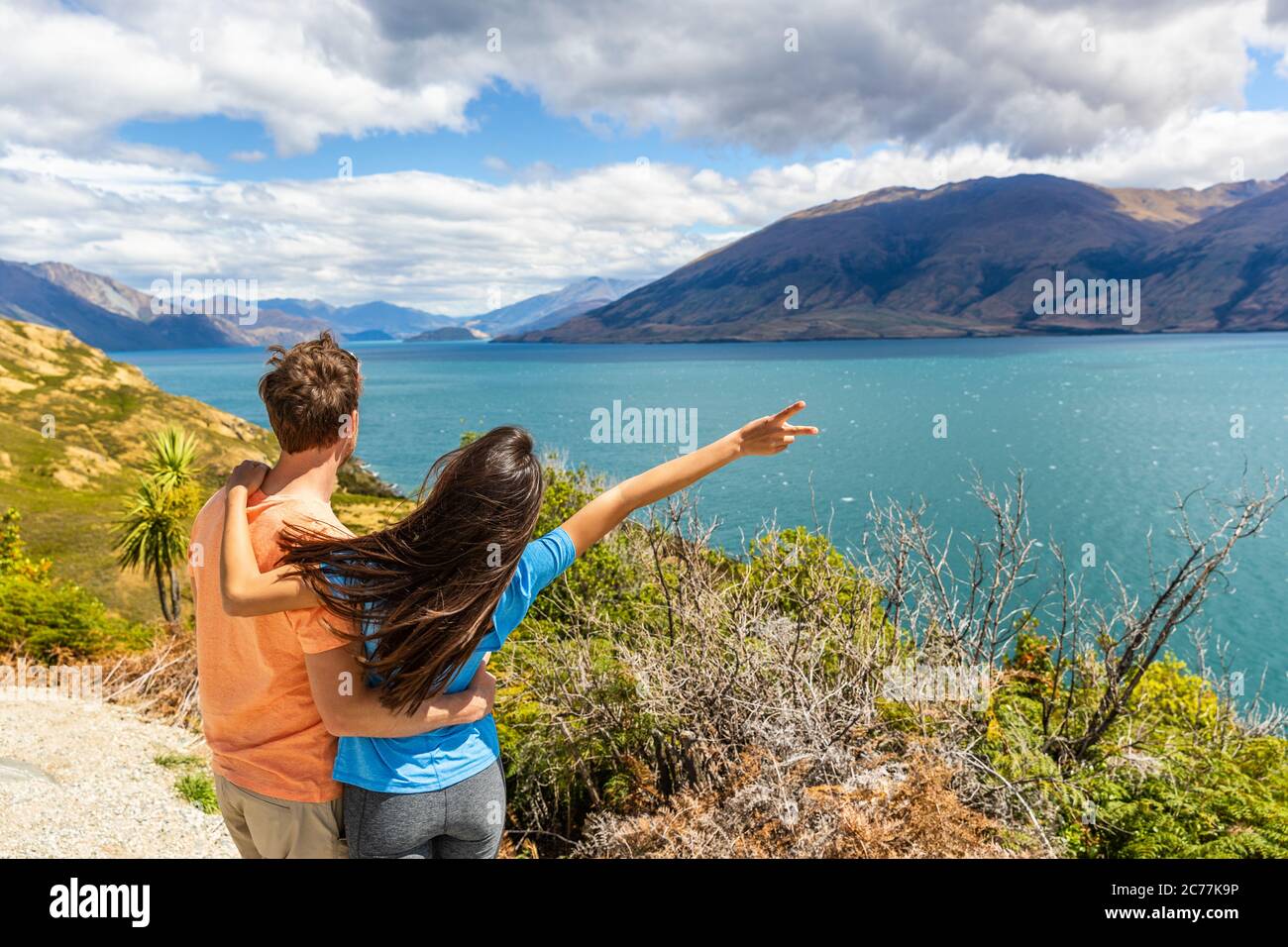 Coppia di viaggio che si gode di un viaggio in Nuova Zelanda, donna con braccio in su in eccitazione a Lake view in Nuova Zelanda. Trampers viaggio destinazione estiva Foto Stock