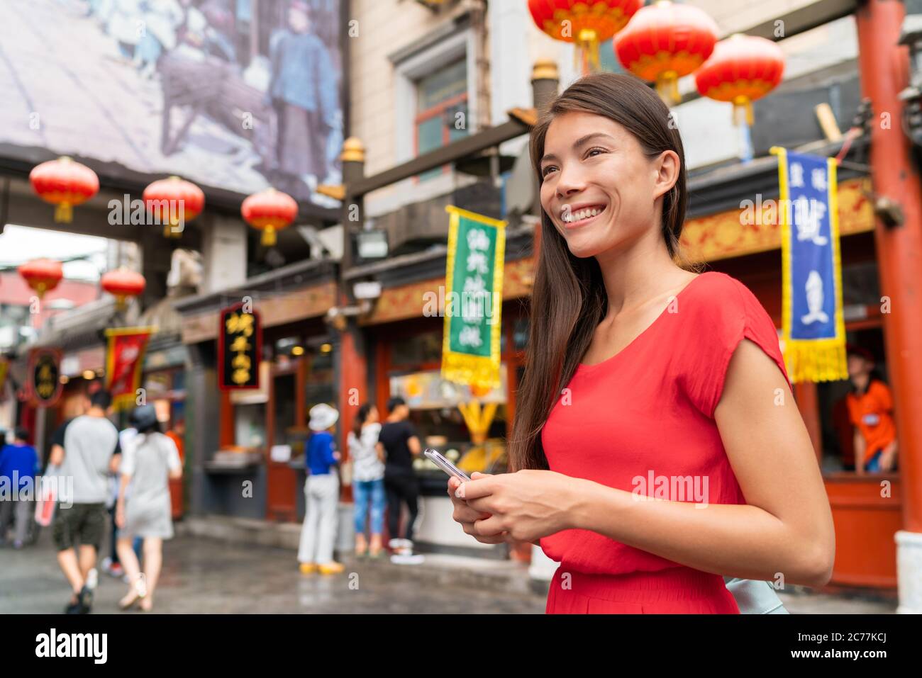Cina mercato alimentare turista donna a piedi utilizzando il telefono su Pechino Hutong strada viaggio avventura vacanza. Città stile di vita giovane ragazza asiatica. Estate in Asia Foto Stock
