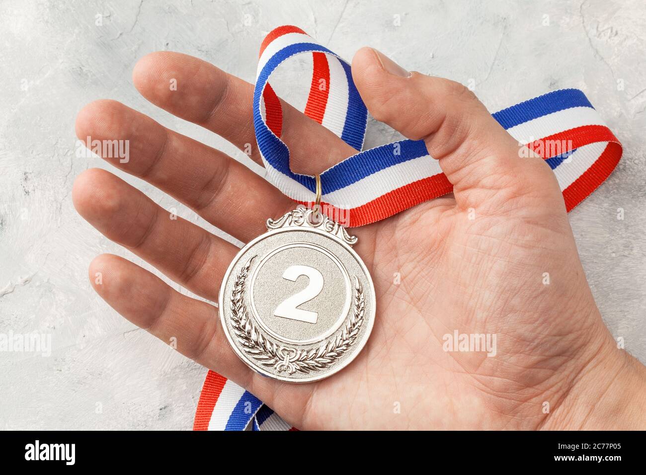 Medaglia d'argento. Il secondo premio con un nastro che un uomo tiene in mano. Foto Stock