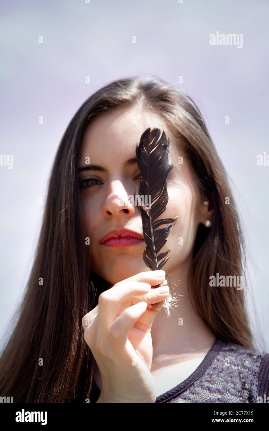 Donna che ricopre il suo occhio con Feather Foto Stock