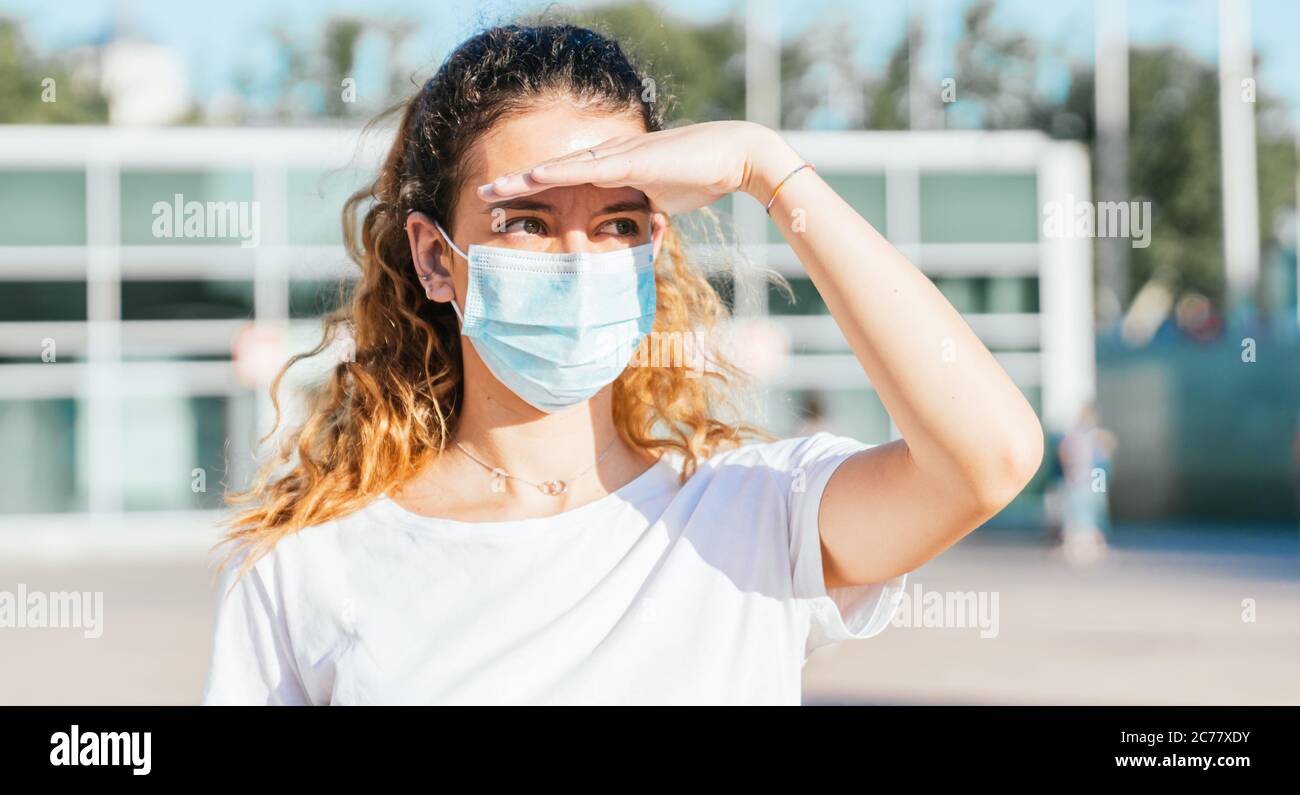 Nuovo normale. Ragazza giovane con una maschera per strada. Giovane ragazza in maschera sulla strada segnalando di cercare qualcuno. Foto Stock