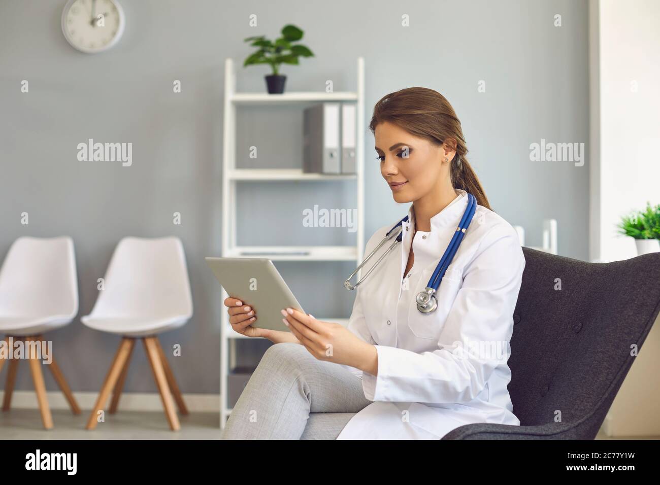 Medico femminile con tablet che parla con il cliente online dalla clinica. Medico professionale in videoconferenza con il paziente Foto Stock