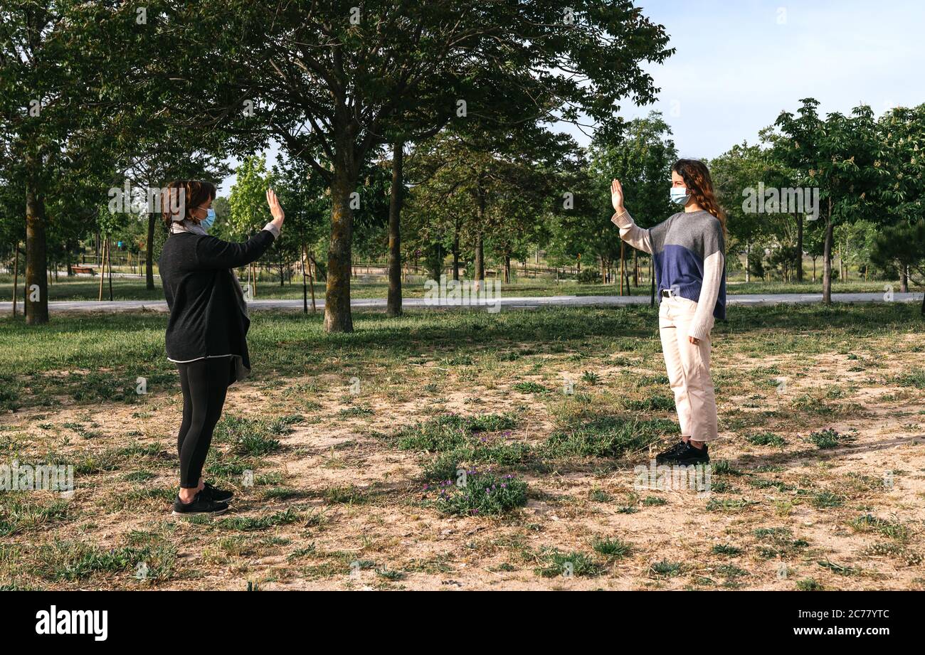 Distanza sociale. Due vicini camminano attraverso un parco e si salutano mentre mantengono la loro distanza dalla pandemia. Pandemia. Dispositivi coronavirus. Foto Stock