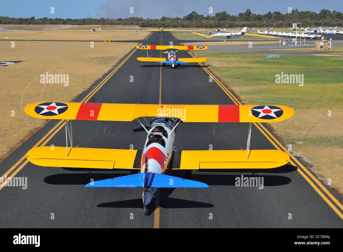 Un ritratto da aria a terra, di due addestratori biplanari restaurati della Marina militare americana Boeing Stearman degli anni '40 che tassano in un campo aereo. Foto Stock