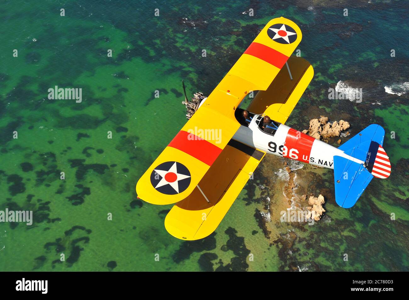 Un ritratto BirdsEye Air to Air, di un allenatore biplanare Stearman Boeing della Marina degli Stati Uniti restaurato degli anni '40 sull'oceano. Foto Stock