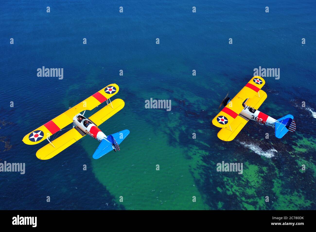 Un ritratto air-air di due addestratori biplanari Stearman della Marina degli Stati Uniti restaurati degli anni '40, con sfondo oceano Foto Stock