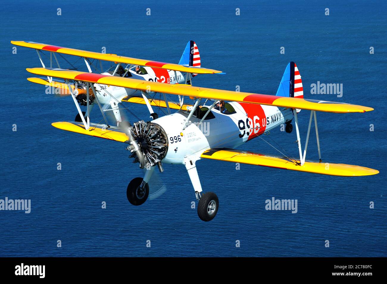 Un ritratto aria-aria di due addestratori biplanari Stearman della Marina degli Stati Uniti restaurati degli anni '40 in formazione sull'oceano. Foto Stock