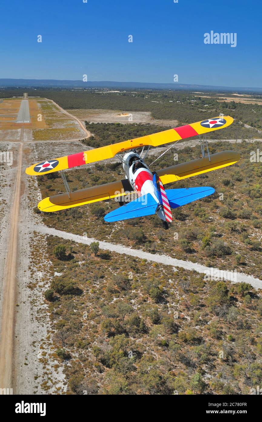 Un ritratto aria-aria, di un addestratore biplano Stearman della Marina militare americana degli anni '40 restaurato che si avvicina ad un campo aereo. Foto Stock