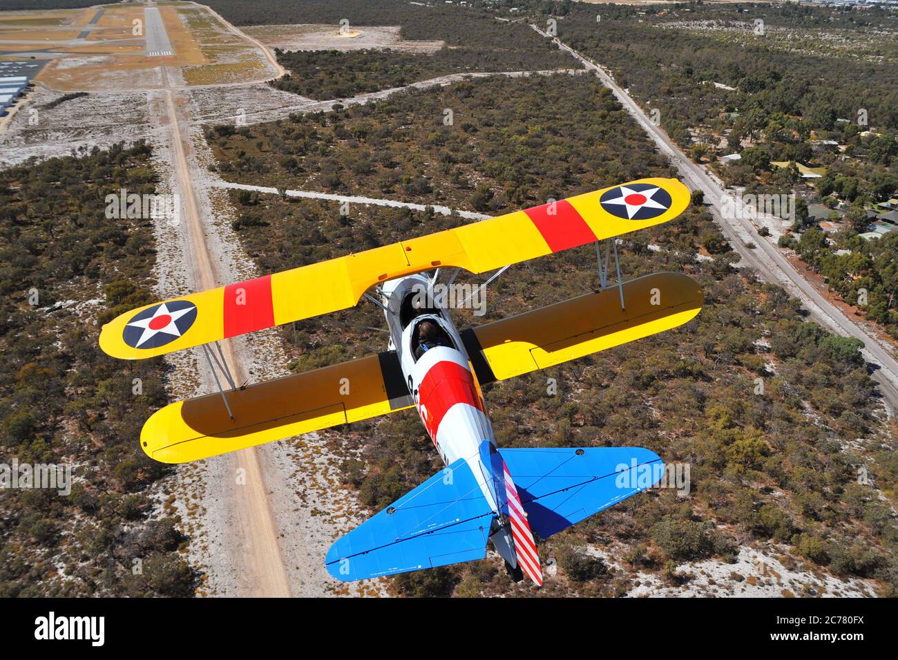 Un ritratto aria-aria, di un addestratore biplano Stearman della Marina militare americana degli anni '40 restaurato che si avvicina ad un campo aereo. Foto Stock