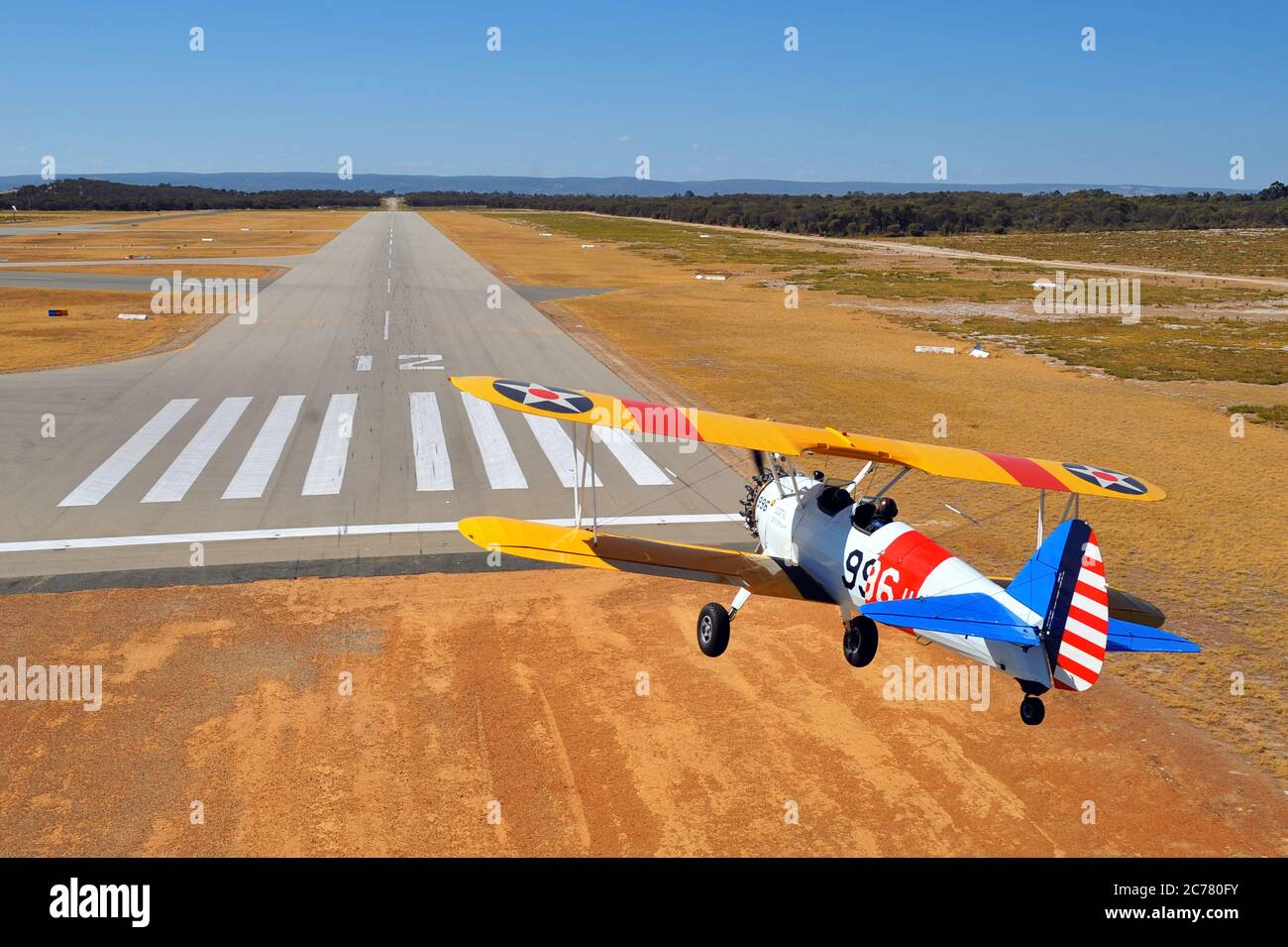 Un ritratto aria-aria, di un addestratore biplano Stearman della Marina militare americana degli anni '40 restaurato che si avvicina ad un campo aereo. Foto Stock