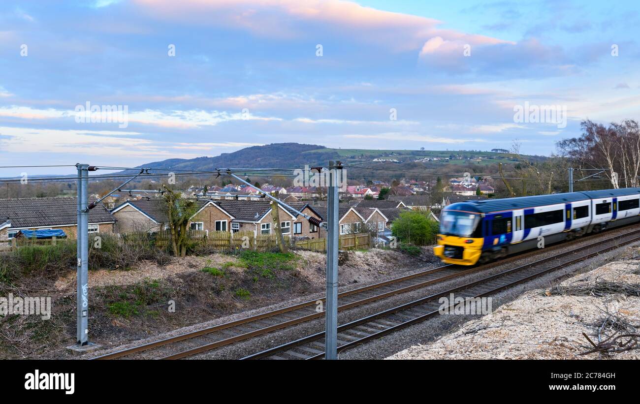 Treno di servizio passeggeri della Northern Rail che viaggia sulle piste ferroviarie della Wharfedale Line, passando per le case nel villaggio rurale - Burley, Yorkshire, Inghilterra, Regno Unito. Foto Stock