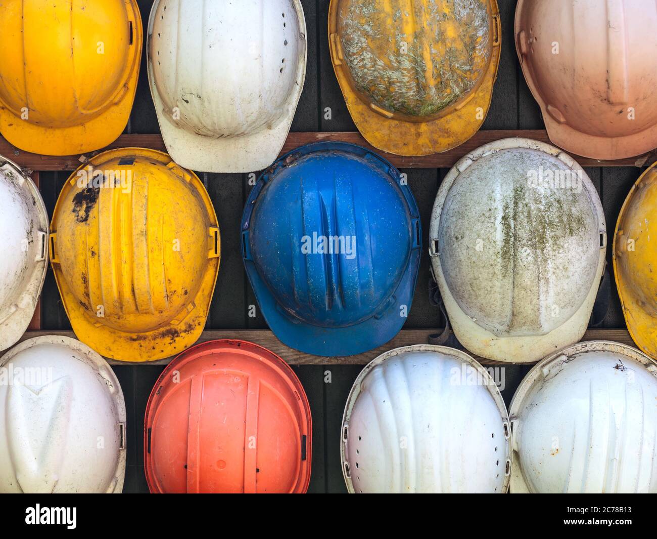 Caschi colorati di costruzione vecchi e indossati Foto Stock