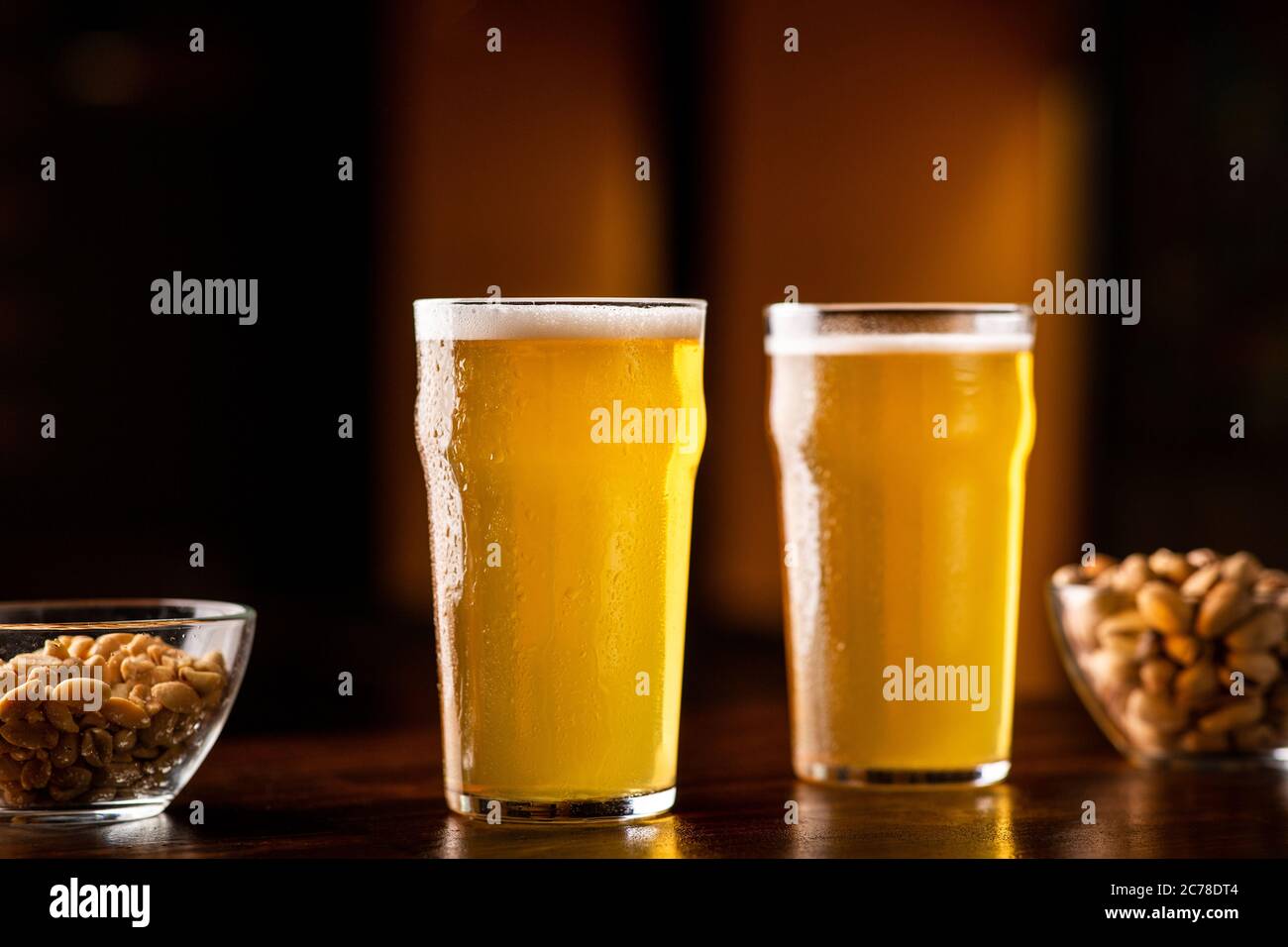 Birra nel pub. Due bicchieri di birra chiara, noci e pistacchi sul tavolo all'interno Foto Stock