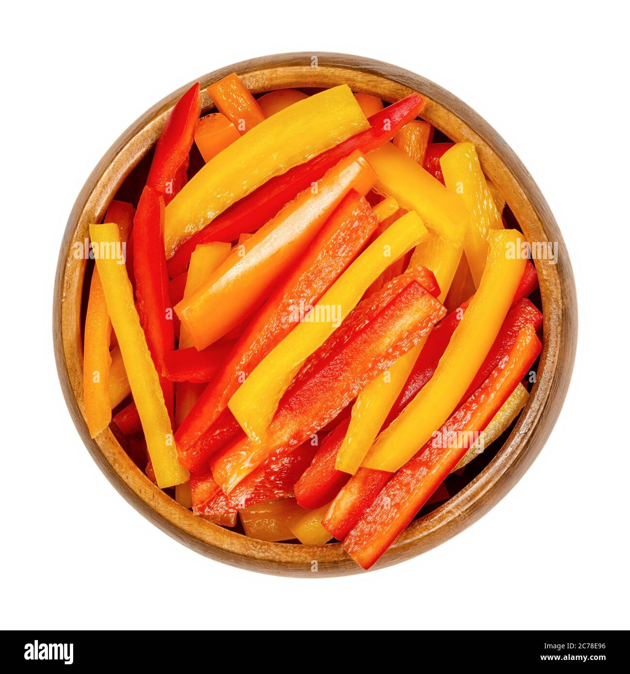 Un mucchio di peperoni a fette in una ciotola di legno. Peperone dolce o capsicum tagliato a strisce colorate. Frutta fresca gialla, arancione e rossa. Foto Stock