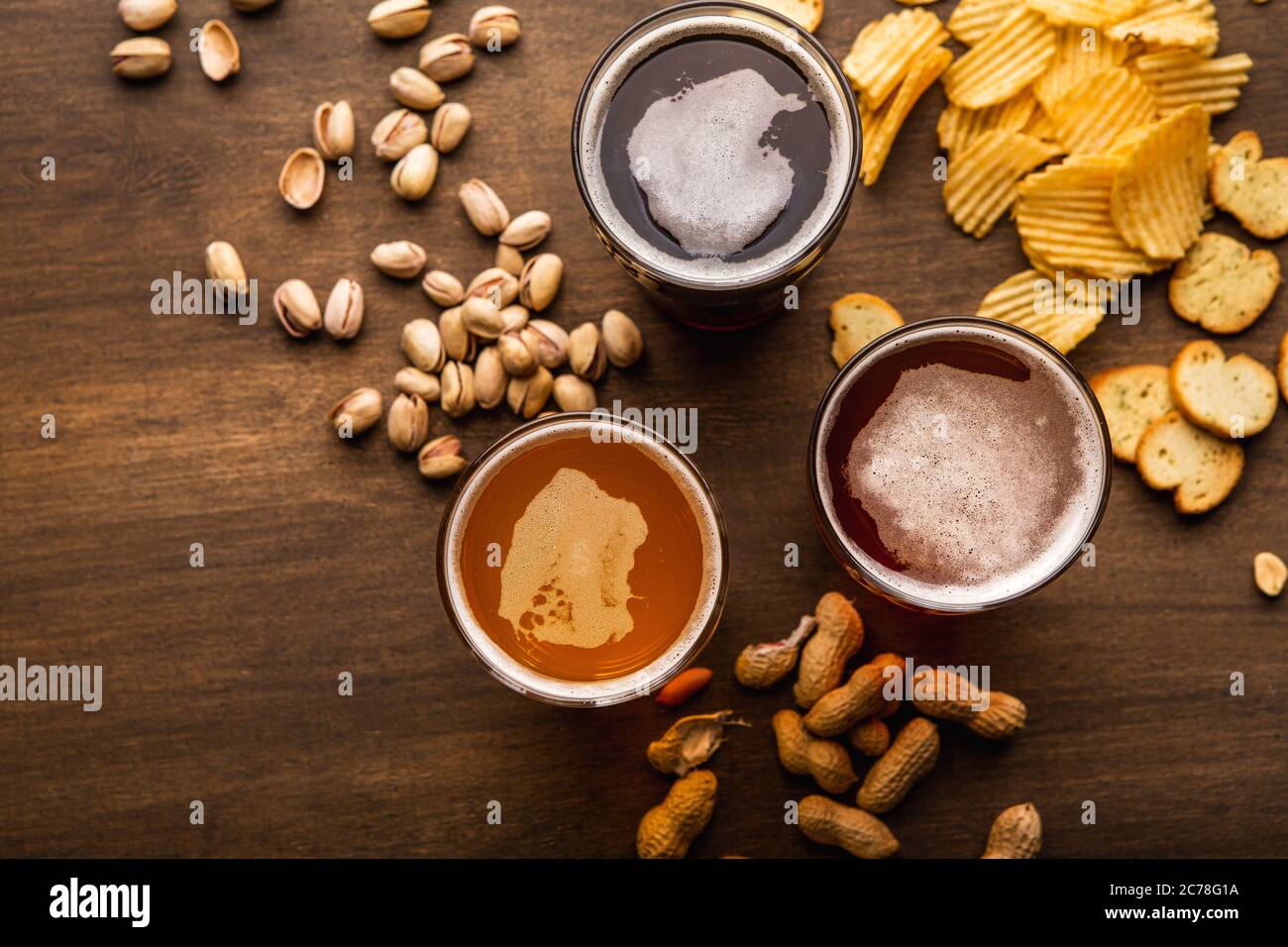 Moderna industria della birra. Birra scura, chiara, non filtrata in bicchieri e spuntini, sparsi su un tavolo di legno Foto Stock