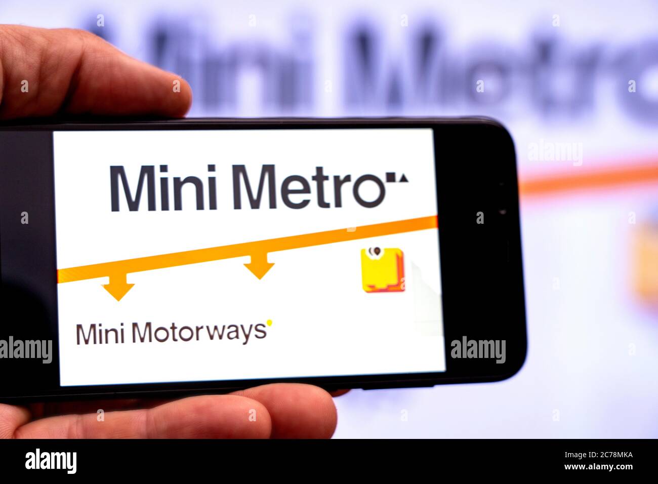 Berlino - Luglio, 2020: Smartphone con il gioco della Mini Metro sullo sfondo di un grande schermo. Giocare Metropolitan Foto Stock