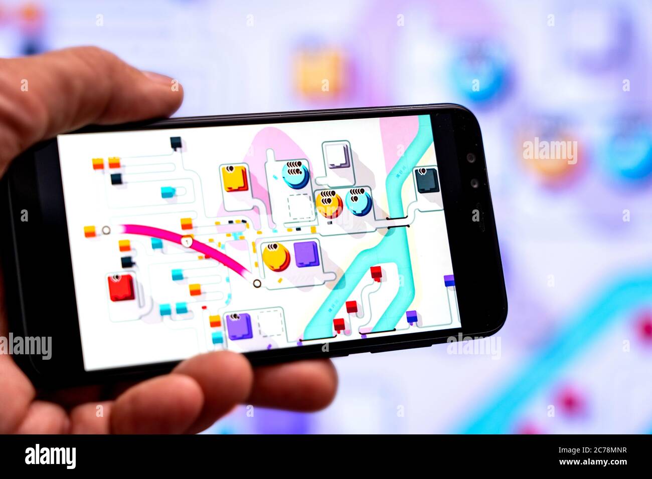 Berlino - Luglio, 2020: Smartphone con il gioco della Mini Metro sullo sfondo di un grande schermo. Giocare Metropolitan Foto Stock