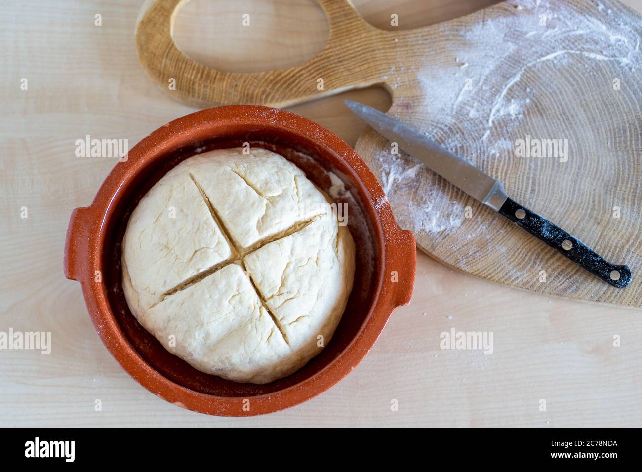 Impasto di pane con croce tagliata sopra su sano, casereccio di pane soda irlandese in una ciotola rossa in ceramica. Panetteria domestica. Foto Stock