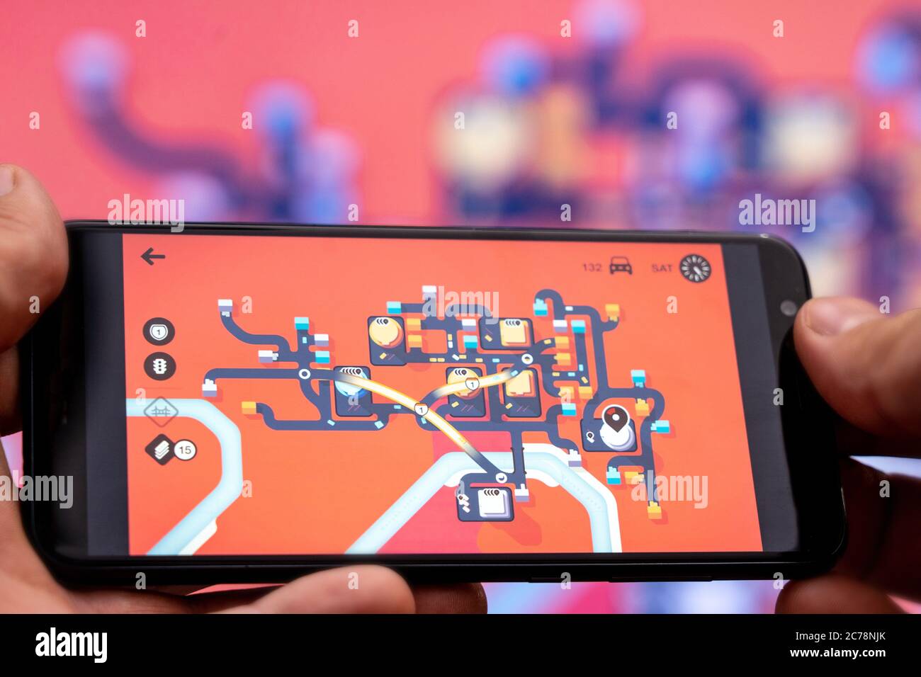 Berlino - Luglio, 2020: Smartphone con il gioco della Mini Metro sullo sfondo di un grande schermo. Giocare Metropolitan Foto Stock