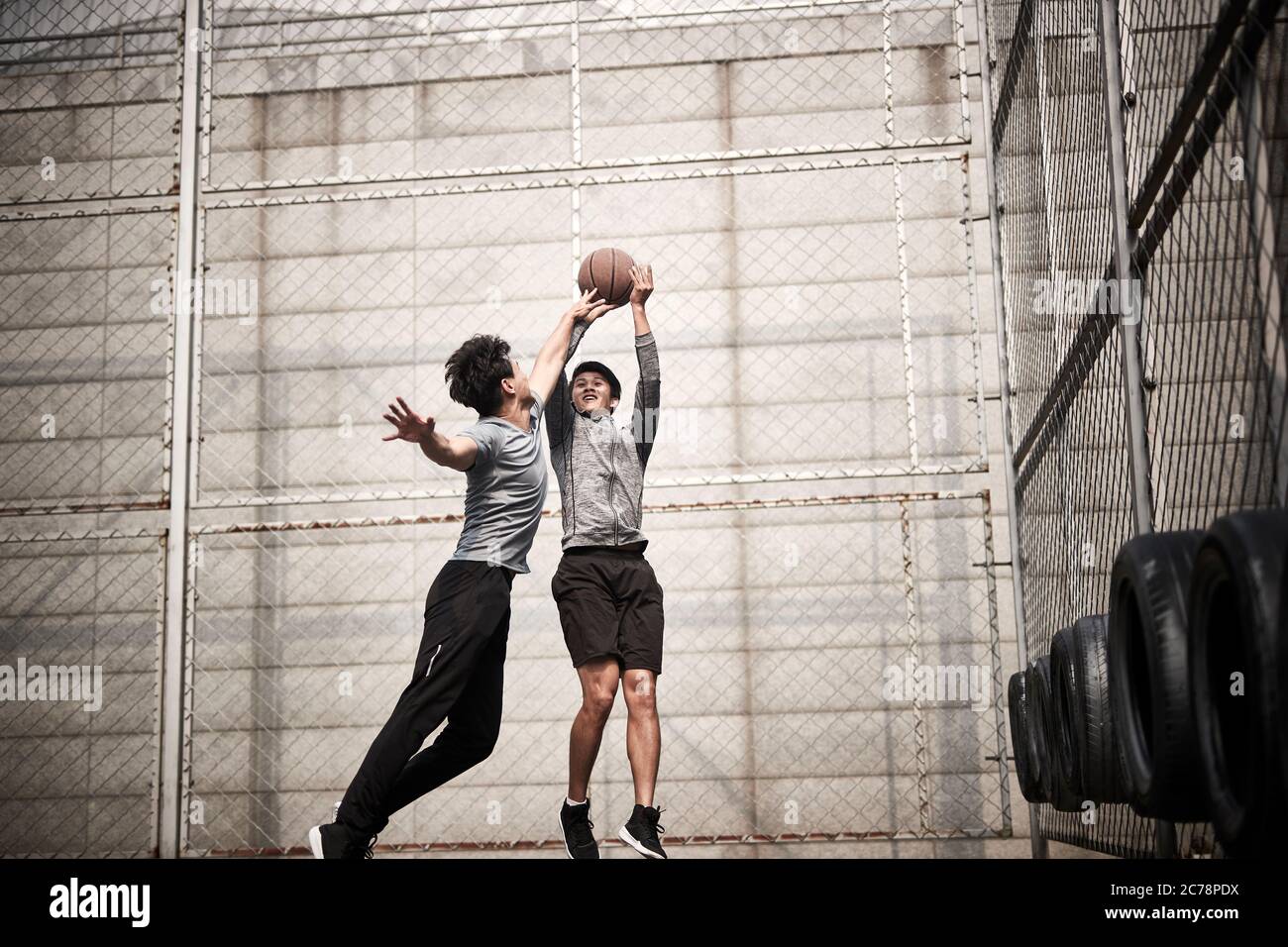 due giovani uomini adulti asiatici che giocano a basket uno a uno sul campo all'aperto Foto Stock