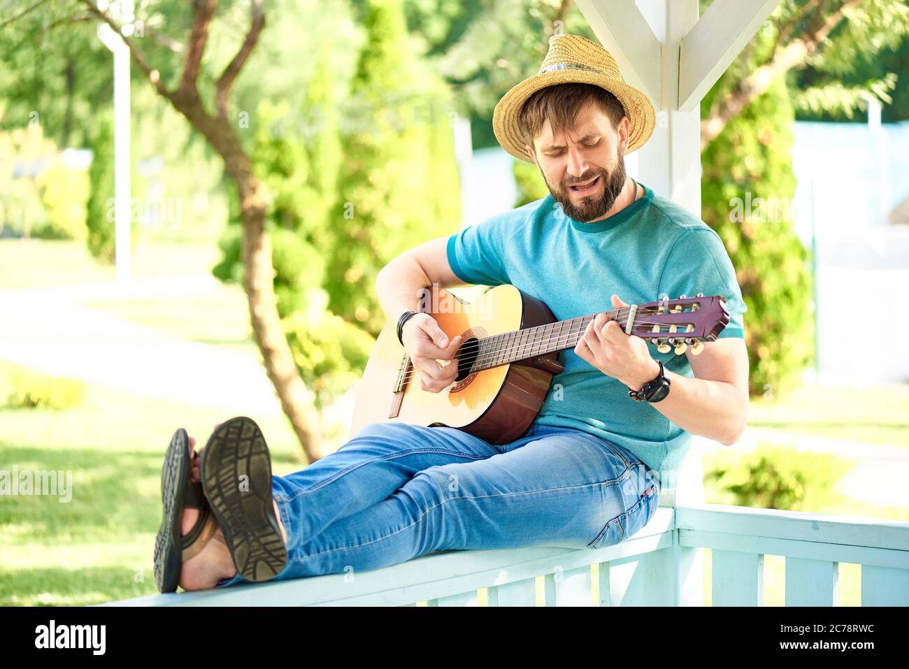 Un giovane suona la chitarra nel giardino estivo. Foto Stock