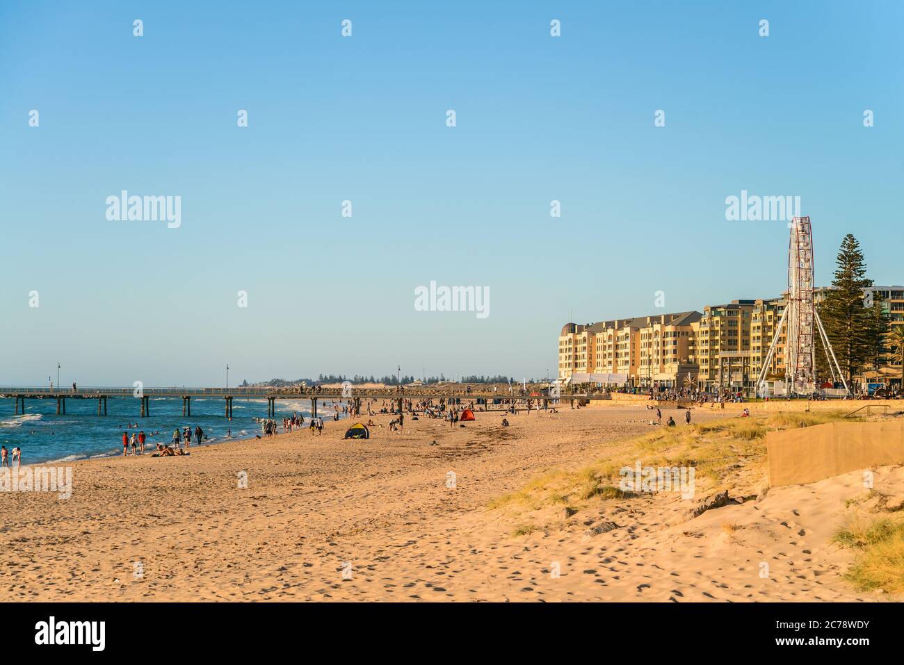 Adelaide, Australia del Sud - 12 gennaio 2019: Persone che trascorrono del tempo a Glenelg Beach con l'iconica ruota panoramica nelle vicinanze in una giornata estiva luminosa Foto Stock